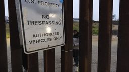Migrantes esperan entre las vallas fronterizas que separan a Tijuana, México, de San Diego, EEUU, para solicitar asilo a las autoridades estadounidenses, el viernes 12 de abril de 2024, vistos desde San Diego. (AP Foto/Gregory Bull)