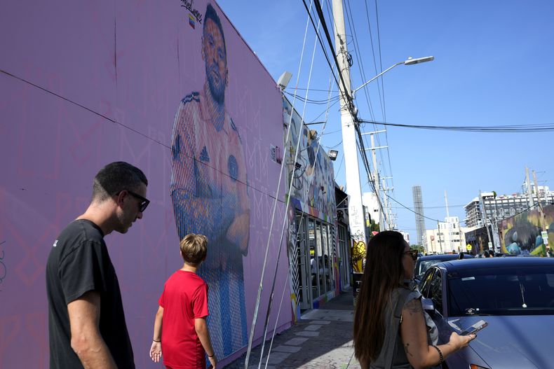 Un grupo de personas caminan frente a un mural del astro argentino del fútbol Lionel Messi hecho por Arlex Campos en Miami, el domingo 9 de julio de 2023 (AP Foto/Lynne Sladky)