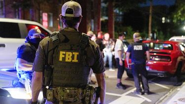 Oficiales de varias agencias federales, incluidos el FBI y la Policía de Parques, interrogan a una pareja que estaba comiendo afuera de un estacionamiento, el martes 12 de agosto de 2025, en el noroeste de Washington, cerca de Kennedy St. NW. La pareja fue liberada después que les registraron el automóvil. (AP Foto/Jacquelyn Martin)
