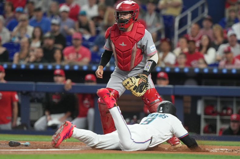 Xavier Edwards (9) de los Marlins de Miami anota una carrera frente al receptor P.J. Higgins de los Rojos de Cincinnati, el jueves 9 de abril de 2026, en Miami. (AP Foto/Marta Lavandier)