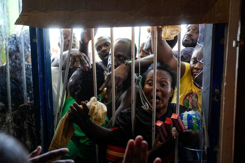 Residentes se agolpan alrededor de un supermercado cerrado en Black River, Jamaica, el jueves 30 de octubre de 2025, tras el paso del huracán Melissa. (AP Foto/Matías Delacroix)