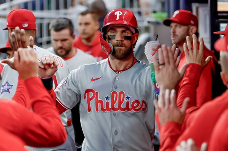 Bryce Harper de los Filis de Filadelfia es recibido en la caseta tras anotar contra los Bravos de Atlanta durante la primera entrada de un partido de béisbol, el sábado 25 de abril de 2026, en Atlanta. (AP Foto/Erik S. Lesser)