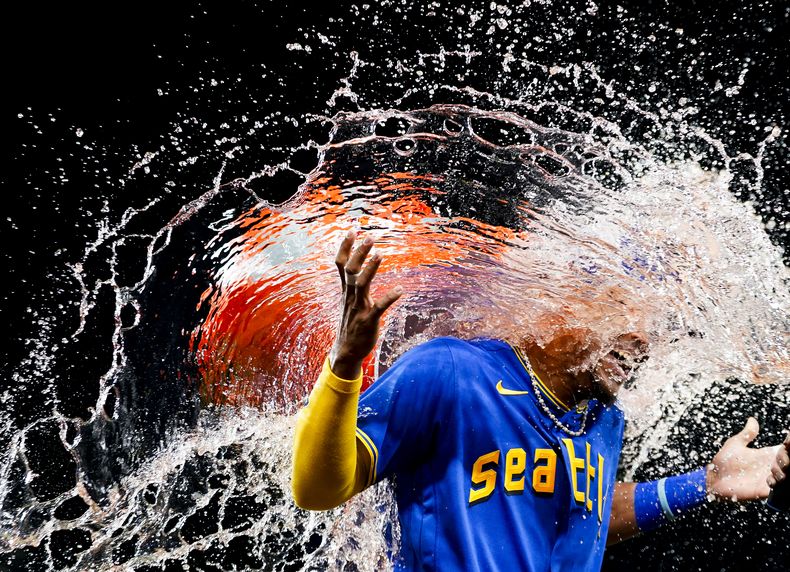 El dominicano Julio Rodríguez, de los Marineros de Seattle, es empapado por su compatriota y compañero Teoscar Hernández tras el triunfo sobre los Orioles de Baltimore, el viernes 11 de agosto de 2023 (AP Foto/Lindsey Wasson)