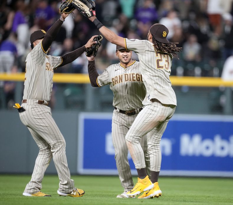 Los dominicanos Juan Soto (izquierda) y Fernando Tatis Jr. (derecha), de los Padres de San Diego, festejan con su compañero Trent Grisham la victoria sobre los Rockies de Colorado, el 9 de junio de 2023 (AP Foto/David Zalubowski)