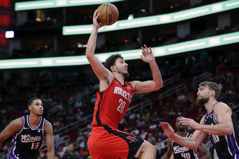 Alperen Sengun (28), de los Rockets de Houston, ataca el aro entre Keegan Murray (13) y Domantas Sabonis (10), de los Kings de Sacramento, durante la segunda mitad del juego de baloncesto de la NBA, el lunes 6 de noviembre de 2023, en Houston. (AP Foto/Michael Wyke)