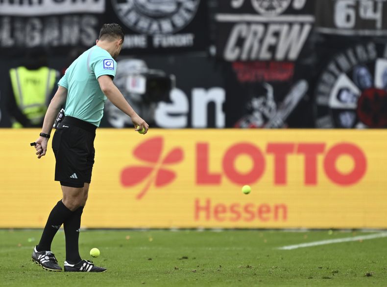 El árbitro Daniel Schlager observa una pelota arrojada al campo de juego durante el partido de la Liga de Alemania entre el Eintracht Fráncfort y el Wolfsburgo en el Deutsche Bank Park, en Fráncfort, Alemania, el domingo 25 de febrero de 2024. (Arne Dedert/dpa via AP)