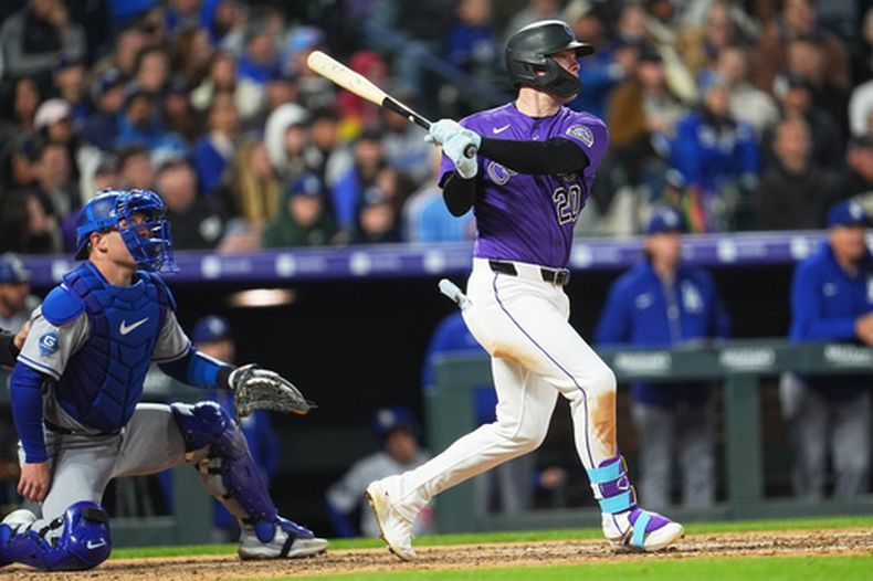 Troy Johnston de los Rockies de Colorado le da seguimiento a su doble de dos carreras ante los Dodgers de Los Ángeles el sábado 18 de abril del 2026. (AP Foto/David Zalubowski)
