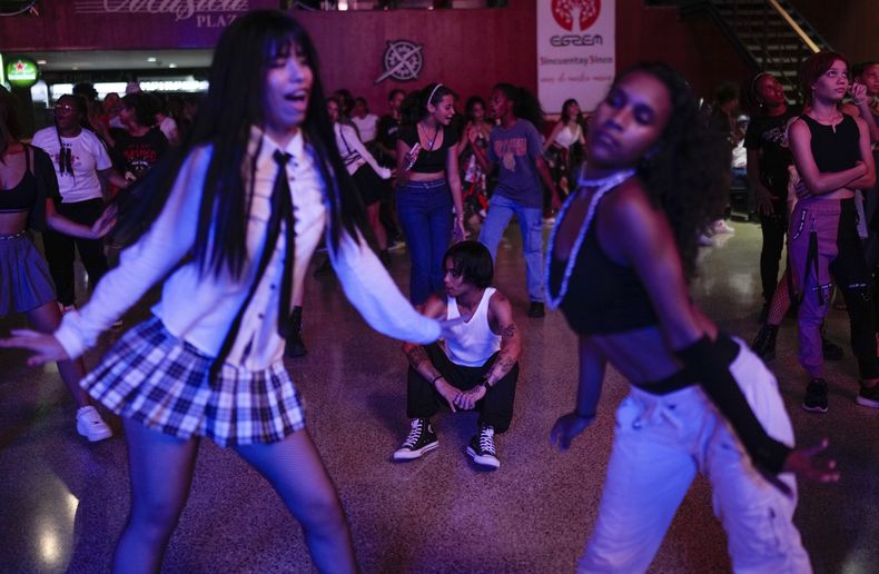 El bailarín Francisco Piedra, de 24 años, conocido por el nombre artístico de Ken, descansa en el suelo al fondo mientras otros jóvenes bailan al ritmo del K-pop, música popular coreana en una casa cultural en La Habana, Cuba, el sábado 7 de septiembre de 2024. (Foto AP/Ramón Espinosa)