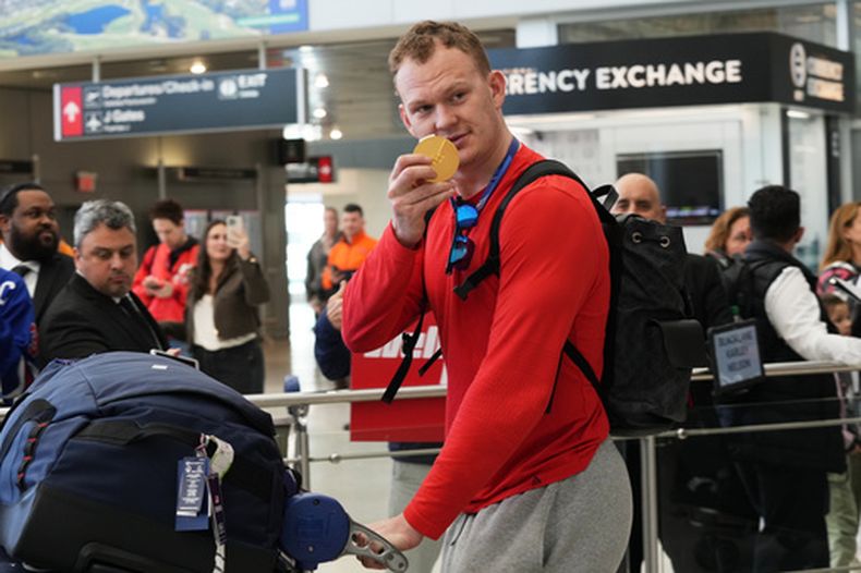 El jugador de hockey estadounidense Brady Tkachuk muestra la medalla de oro al llegar al aeropuerto de Miami tras los Juegos Olímpicos de Invierno el lunes 23 de febrero del 2026. (AP Foto/Marta Lavandier)
