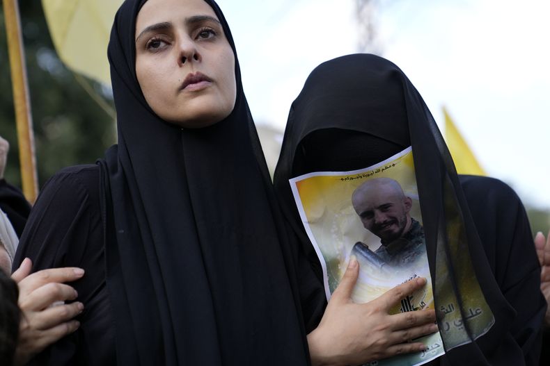 La esposa, a la izquierda, y la hermana del miembro de Hezbollah Ali Ftouni, quien murió en una ofensiva israelí, se lamentan durante su procesión fúnebre, el martes 10 de octubre de 2023, en el poblado de Khirbet Selm, en el sur de Líbano. El grupo respaldado por Irán anunció el lunes por la noche que tres de sus combatientes murieron luego de un intenso ataque de Israel contra poblados en el sur de Líbano. (AP Foto/Hussein Malla)