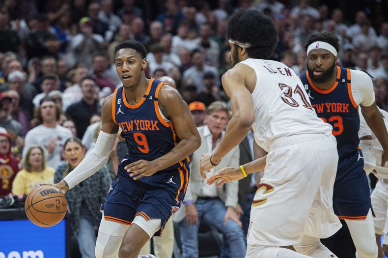 RJ Barrett (9), de los Knicks de Nueva York, conduce el balón frente a Jarrett Allen (31), de los Cavaliers de Cleveland, mientras Mitchell Robinson (23), de Nueva York, observa durante la segunda mitad del Juego 5 de la serie de primera ronda del baloncesto de la NBA, el miércoles 26 de abril de 2023, en Cleveland. Los Knicks ganaron 106-95 y se llevaron la serie. (AP Foto/Phil Long)
