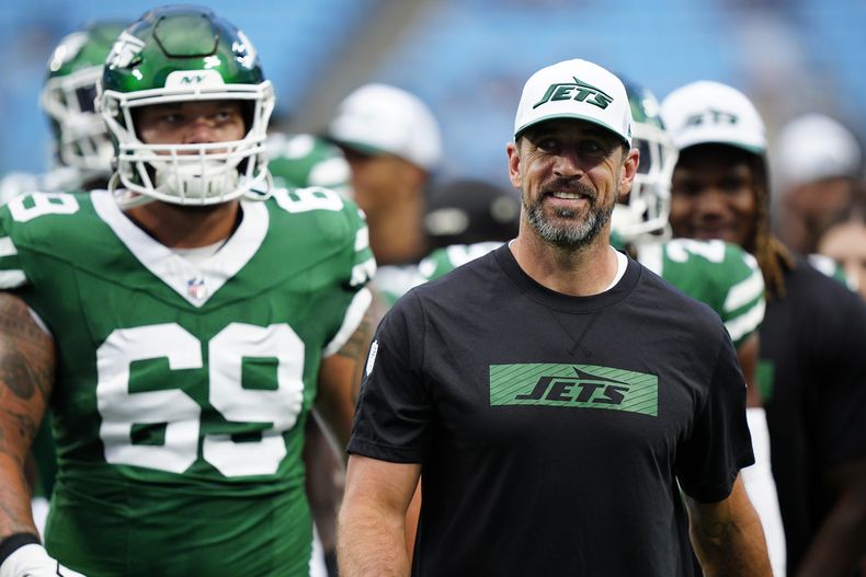 Aaron Rodgers (derecha), quarterback de los Jets de Nueva York, ingresa en el terreno con sus compañeros antes de un encuentro de pretemporada ante los Panthers de Carolina, el sábado 17 de agosto de 2024 (AP Foto/Jacob Kupferman)