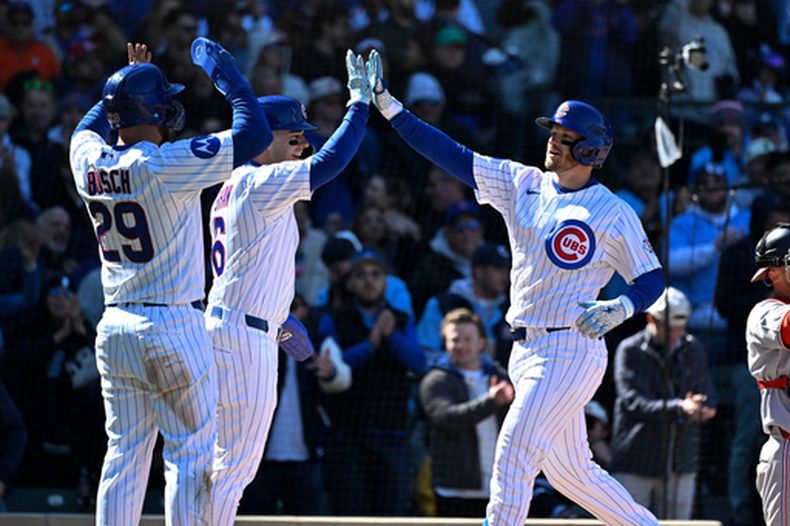 Ian Happ le da los cinco a su compañero de los Cachorros Matt Shaw y Michael Busch después de que anotaron en su jonrón de tres carreras en la sexta entrada ante los Nacionales de Washington el sábado 28 de marzo del 2026. (AP Foto/Matt Marton)