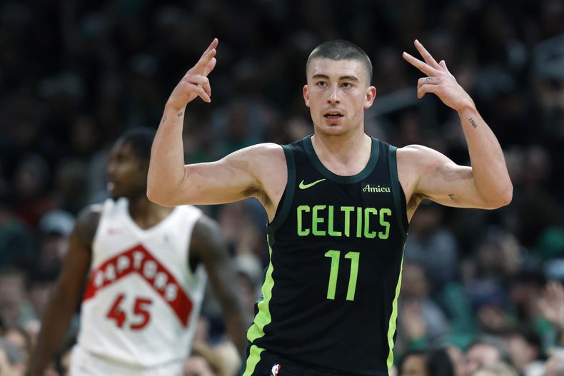 Payton Pritchard (11), de los Celtics de Boston, celebra su triple frente a Davion Mitchell (45), de los Raptors de Toronto, durante la primera mitad de un partido de baloncesto de la NBA, el martes 31 de diciembre de 2024, en Boston. (AP Foto/Michael Dwyer)