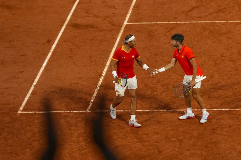 La pareja española de Carlos Alcaraz, a la izquierda, y Rafael Nadal celebran un punto durante el partido de dobles ante los argentinos Andrés Molteni y Máximo González en los Juegos Olímpicos de París, el sábado 27 de julio de 2024. (AP Foto/Manu Fernández)
