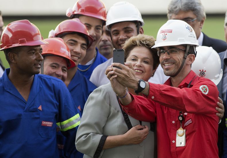 Trabahadores de la construcci&oacute;n se toman una fotograf&iacute;a con la presidenta brasile&ntilde;a Dilma Rousseff durante la visita de ella al estadio Itaquerao, en Sao Paulo, el jueves 8 de mayo de 2014. (Foto AP/Andre Penner)