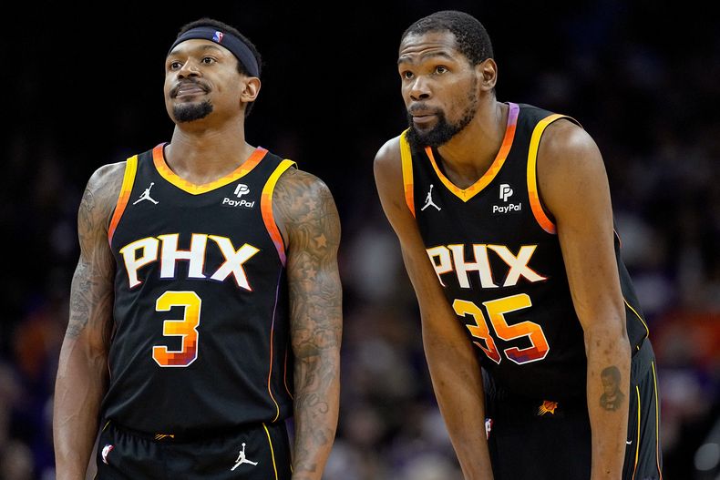 El escolta de los Suns de Phoenix Bradley Beal (3) y el alero Kevin Durant observan un tiro libre durante la segunda mitad del Juego 3 de una serie de playoffs de primera ronda de baloncesto de la NBA contra los Timberwolves de Minnesota, el viernes 26 de abril de 2024, en Phoenix. (AP Foto/Matt York)