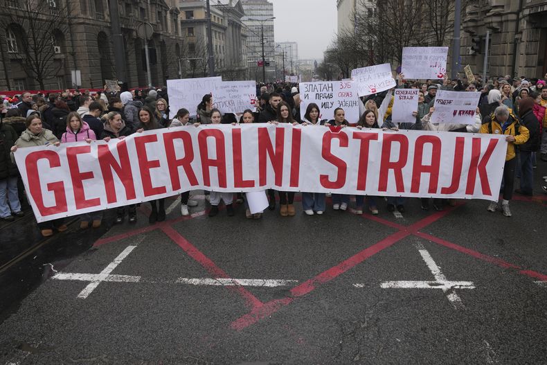 Un grupo de estudiantes sostienen una manta que dice “Paro general” y detienen el tráfico para conmemorar a las 15 víctimas que murieron tras el derrumbe de un dosel de concreto en noviembre, para exigir la rendición de cuentas por la tragedia en Belgrado, Serbia, el viernes 24 de enero de 2025. (AP Foto/Darko Vojinovic)