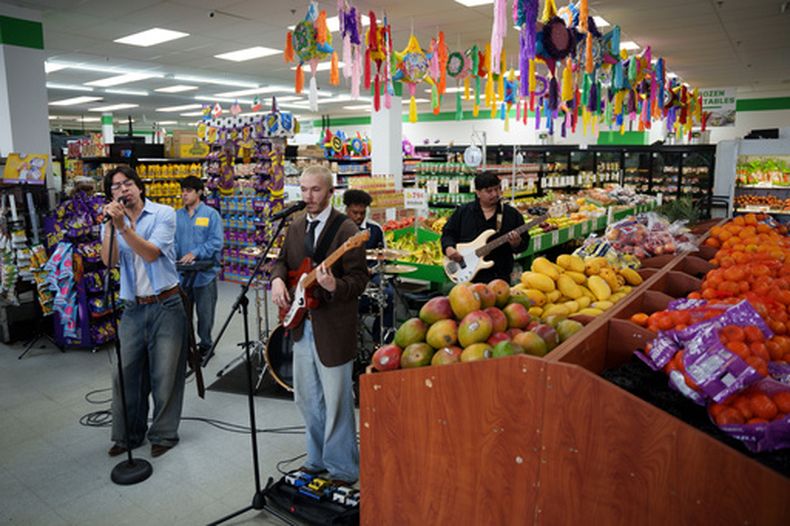 El grupo bilingüe de pop alternativo Luna Luna actuó en la sección de frutas y verduras del mercado Fiesta Fresh Market en New Castle, Delaware, el domingo 26 de abril de 2026. (Foto AP/Mingson Lau)