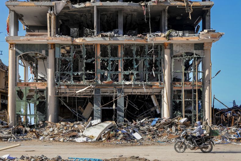 Palestinos pasan en motocicleta junto a un edificio destruido en Ciudad de Gaza el miércoles 29 de noviembre de 2023, en el sexto día del cese el fuego temporal entre Israel y Hamás. (AP Foto/Mohammed Hajjar)