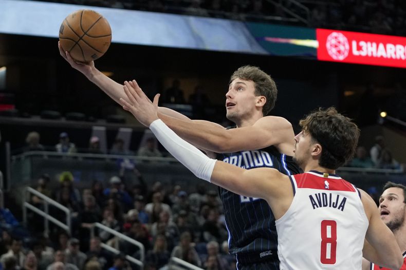 El alero del Magic de Orlando Franz Wagner lanza el balón sobre el alero de los Wizards de Washington Deni Avdija en el encuentro del miércoles 29 de noviembre del 2023. (AP Foto/John Raoux)