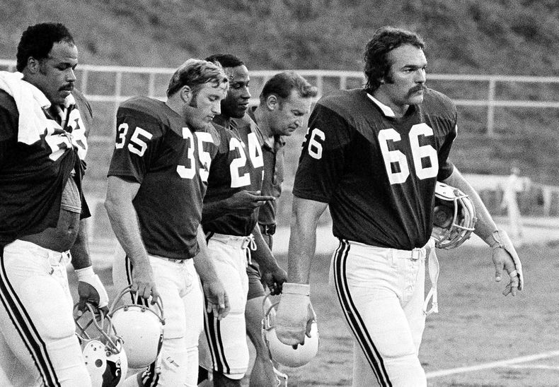 ARCHIVO - Conrad Dobler (66), de los Cardinals de San Luis, encabeza a un grupo de jugadores que salen del campo al final de un entrenamiento de la NFL, en St. Charles, Missouri, el 5 de agosto de 1977. (AP Foto/Archivo)