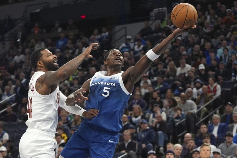 Anthony Edwards (5), de los Timberwolves de Minnesota, dispara superando a Marcus Morris Sr. (24), de los Cavaliers de Cleveland, durante la primera mitad del juego de baloncesto de la NBA, el viernes 22 de marzo de 2024, en Minneapolis. (AP Foto/Abbie Parr)