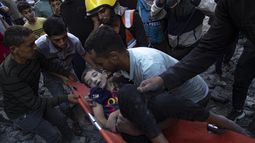 Palestinos evacuan a los heridos tras un bombardeo que destruyó un edificio en Khan Younis, en la Franja de Gaza, el 19 de octubre de 2023. (AP Foto/Fatima Shbair)