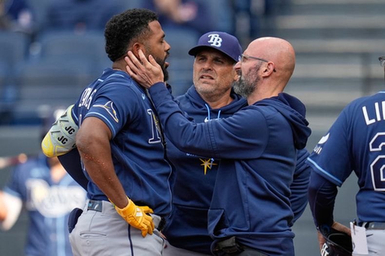 Junior Caminero de los Rays de Tampa Bay es examinado tras ser golpeado por un batazo de foul en la primera entrada de un partido de béisbol contra los Guardianes de Cleveland en Cleveland, el martes 28 de abril de 2026. (AP Foto/Sue Ogrocki)