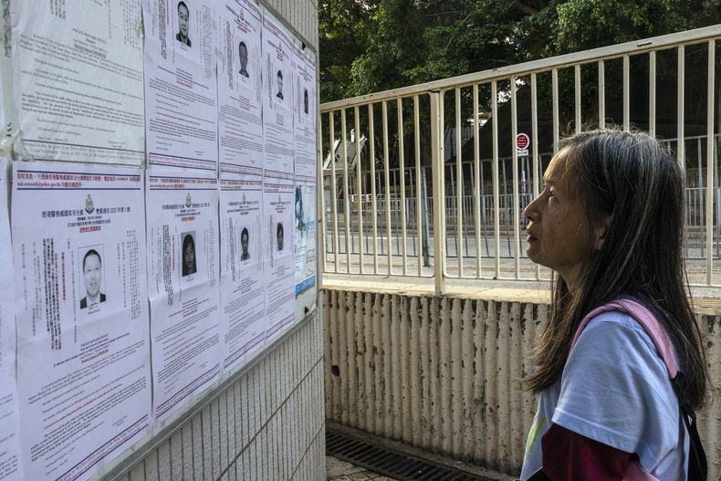 ARCHIVO - Un transeúnte observa los letreros de recompensa para las órdenes de arresto emitidas para ocho activistas a favor de la democracia por presuntas infracciones de seguridad nacional en Hong Kong, el viernes 14 de julio de 2023. (AP Foto/Louise Delmotte, Archivo)