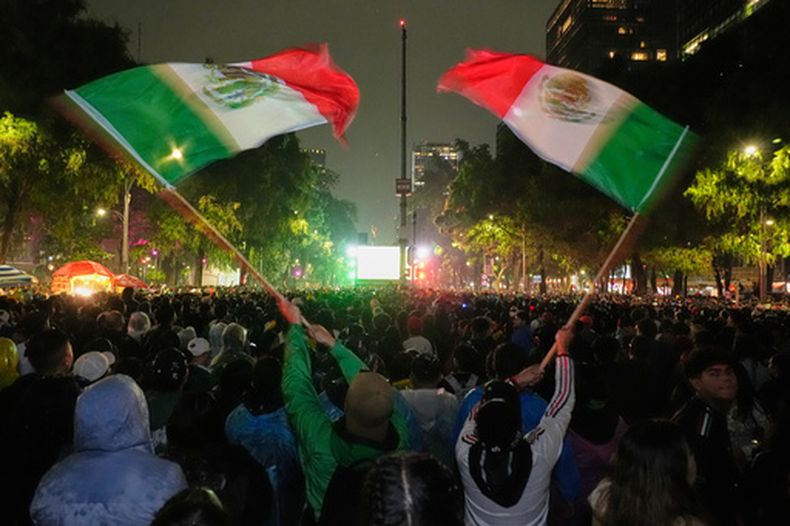 Aficionados mexicanos ondean banderas mientras observan el partido de dieciseisavos de final del Mundial entre México y Ecuador cerca del monumento al Ángel de la Independencia en la Ciudad de México, el martes 30 de junio de 2026. (AP Foto/Marco Ugarte)