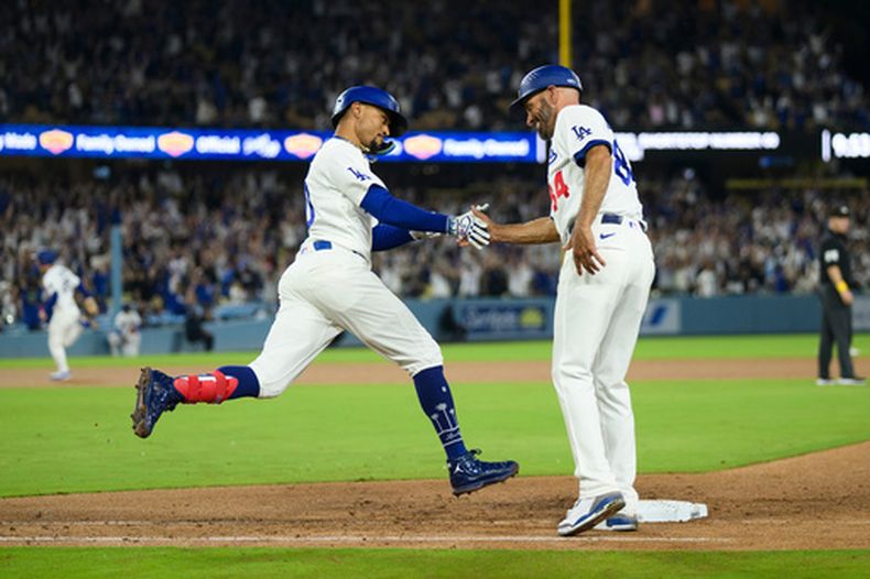 Mookie Betts, izquierda, de los Dodgers de Los Ángeles, celebra su cuadrangular de tres carreras con el coach de primera base, Chris Woodward, durante la octava entrada del juego de béisbol de Grandes Ligas contra los Nacionales de Washington, el domingo 6 de septiembre de 2026, en Los Ángeles. (AP Foto/Kyusung Gong)