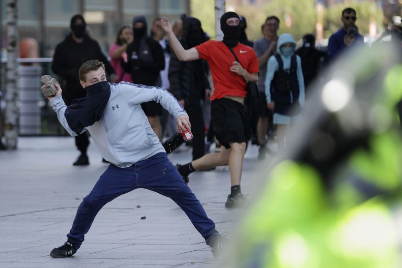 Un manifestante lanza un ladrillo durante una protesta en Liverpool, Inglaterra, el sábado 3 de agosto de 2024. (James Speakman/PA vía AP)