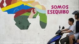 ARCHIVO - Un niño pasa conduciendo una motocicleta frente a un mural con el mapa de Venezuela, que incluye el territorio del Esequibo, en el barrio 23 de Enero de Caracas, Venezuela, el lunes 11 de diciembre de 2023. (AP Foto/Matías Delacroix, archivo)