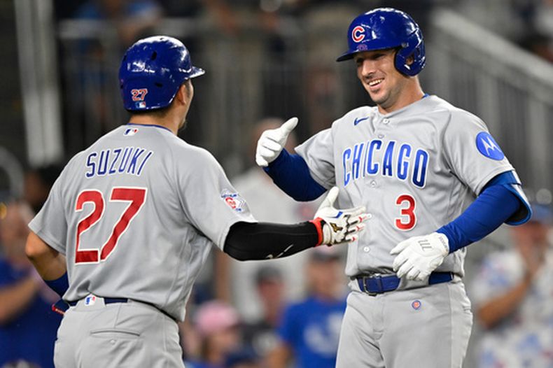 El jardinero de los Cachorros de Chicago, Seiya Suzuki (izquierda), saluda a su compañero Alex Bregman en el plato después de que Bregman conectara un jonrón de dos carreras durante la octava entrada de un partido de béisbol contra los Nationals de Washington, el miércoles 12 de agosto de 2026, en Washington. (Foto AP/John McDonnell)