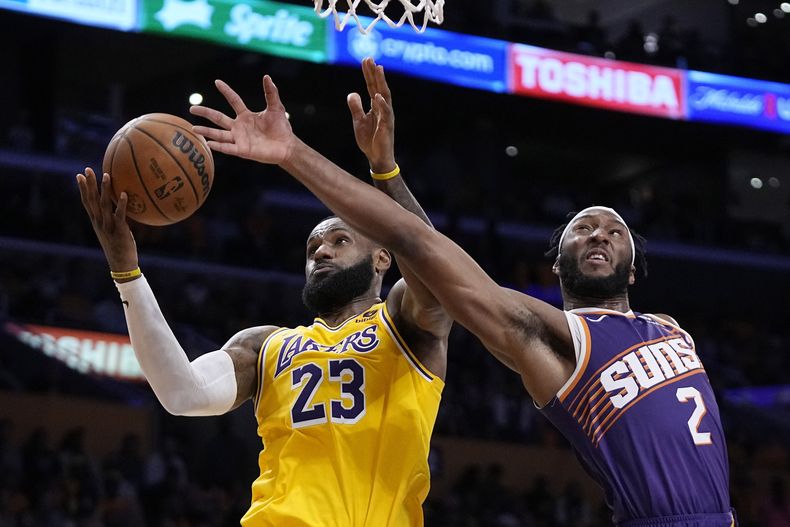 LeBron James, alero de los Lakers de Los Ángeles, atrapa un rebote ante Josh Okogie, de los Suns de Phoenix, el jueves 26 de octubre de 2023 (AP Foto/Mark J. Terrill)