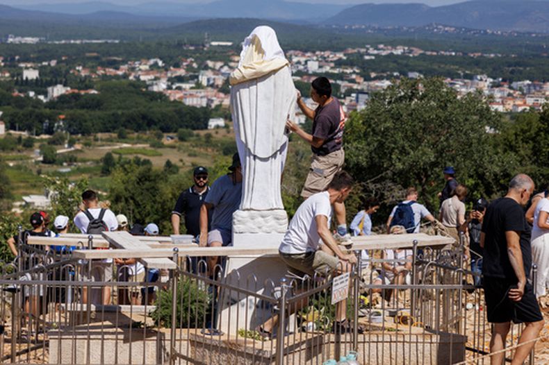 Voluntarios limpian la estatua vandalizada de la Virgen María, que ha sido cubierta con una sábana blanca, en la Colina de las Apariciones en Medjugorje, Bosnia, el 28 de julio de 2026. (Foto AP)