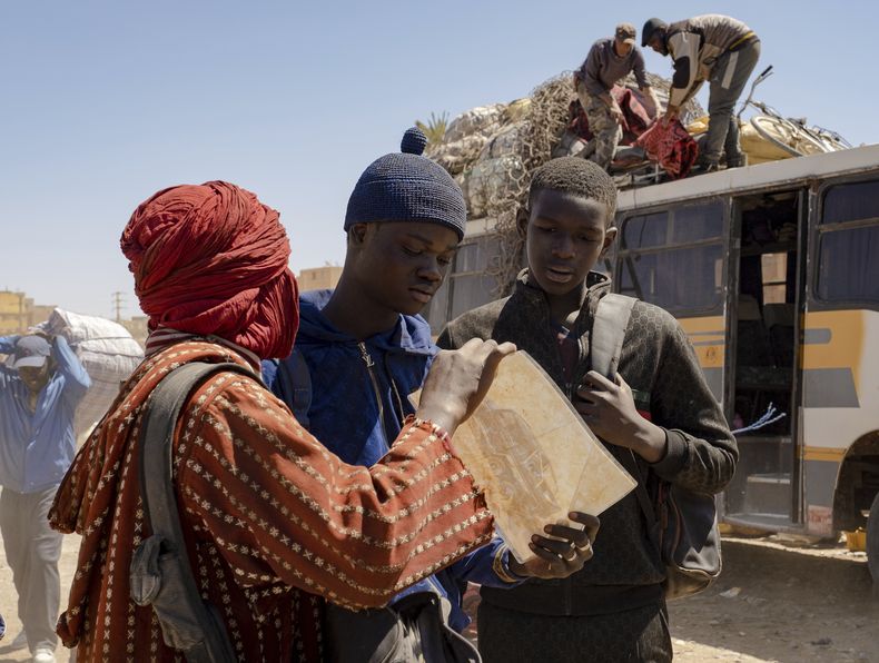 En esta fotografía del 29 de marzo de 2022 proporcionada por 01 Distribuzione, los actores senegaleses Moustapha Fall, centro, y Seydou Sarr, derecha, en el set de la película del director italiano Matteo Garrone Io Capitano (Yo capitán) en el mercado de Rissani, en Marruecos. La película nominada en la 96a entrega de los Premios de la Academia en la categoría de largometraje internacional está inspirada en la travesía de Mamadou Kouassi, un migrante que hizo el viaje desde su natal Costa de Marfil a Italia. (Greta De Lazzaris/01 Distribuzione vía AP, HO)