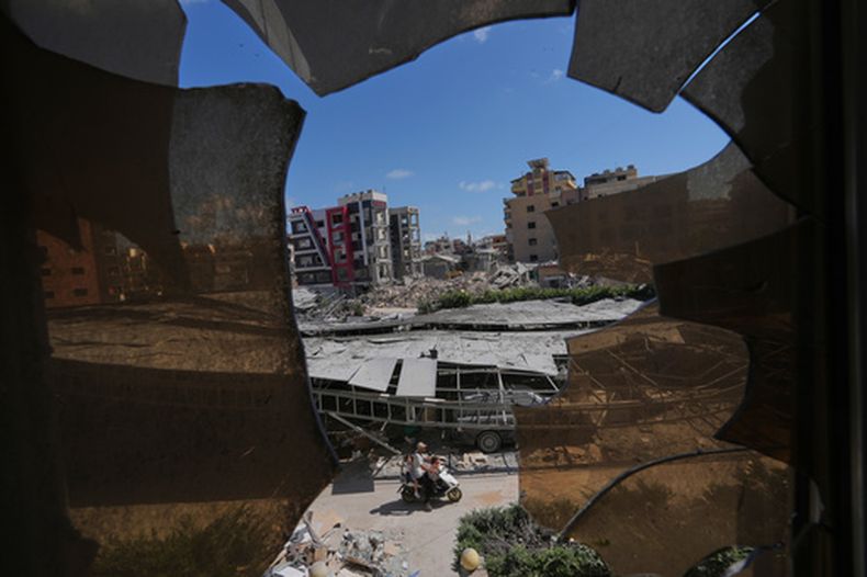 Edificios dañados por ataques israelíes, vistos a través de una ventana rota del hospital Jabal Amel, en la ciudad portuaria de Tiro, en el sur de Líbano, el 18 de junio de 2026. (AP Foto/Hassan Ammar)