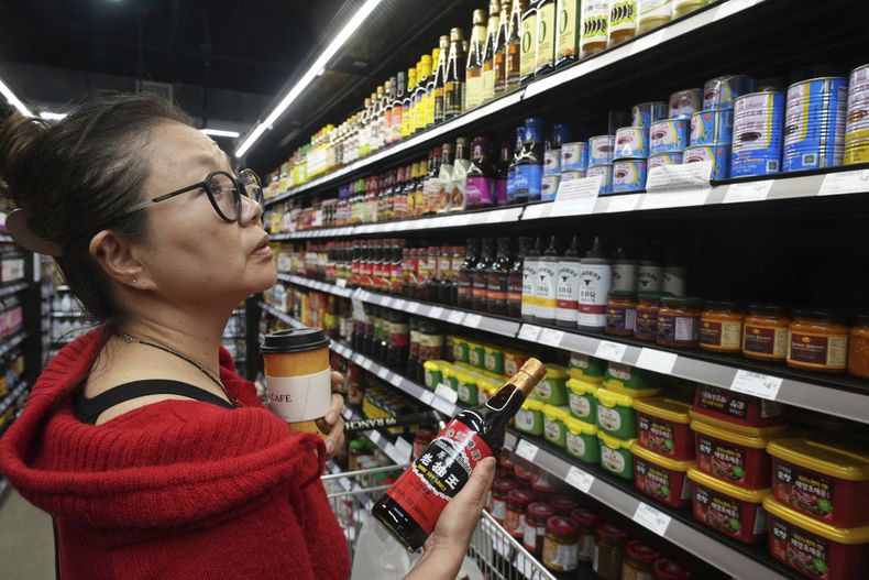 La chef Miki Fujiwara compra salsa de soja Pearl River de China en 99 Ranch Market, una tienda de comestibles asiática en Los Ángeles, el lunes 7 de abril de 2025. (AP Foto/Damian Dovarganes)
