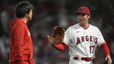 El japonés Shohei Ohtani habla con el intérprete Ippei Mizuhara al abandonar el montículo en la sexta entrada del juego ante los Astros de Houston, e viernes 14 de julio de 2023 (AP Foto/Ashley Landis)