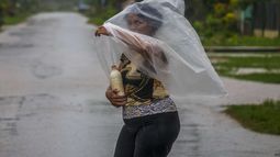 Una mujer usa una bolsa de plástico para cubrirse de las fuertes lluvias provocadas por el huracán Helene, el miércoles 25 de septiembre de 2024, en Batabano, Cuba. (AP Foto/Ramón Espinosa)