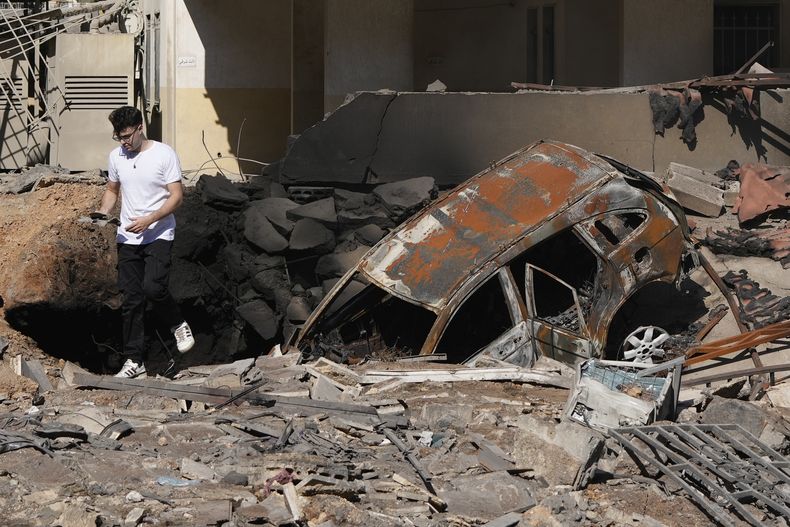 Un hombre camina sobre escombros en el lugar donde se produjo un ataque aéreo israelí, el domingo 29 de septiembre de 2024, en un suburbio de Beirut. (AP Foto/Hassan Ammar)