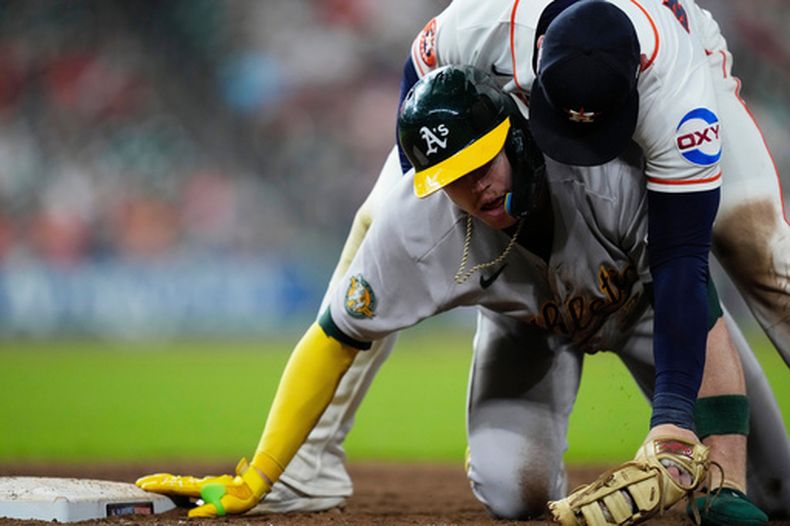 Christian Walker, de los Astros de Houston, cae encima de Henry Bolte, de los Atléticos de Oakland, al retirarlo en el duelo del sábado 22 de agosto de 2026 (AP Foto/Kevin M. Cox)