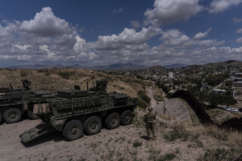 El sargento del Ejército estadounidense Salvador Hernández, parado junto a vehículos de combate Stryker, observa la cerca fronteriza entre Estados Unidos y México desde una colina, el 22 de julio de 2025, en Nogales, Arizona. (AP Foto/Jae C. Hong)