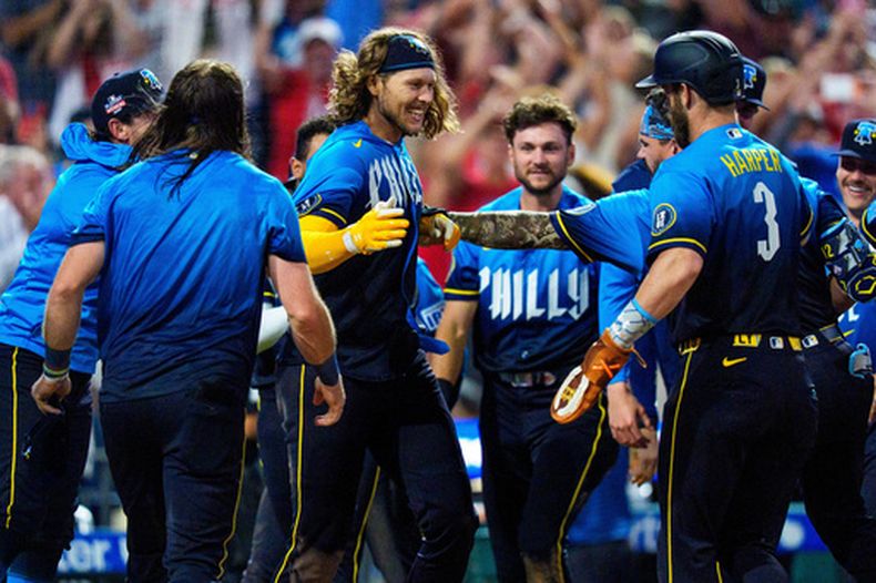 Alec Bohm, centro, de los Filis de Filadelfia, celebra su triple productor de dos carreras para definir la victoria en la 10ma entrada del juego de Grandes Ligas ante los Cardenales de San Luis, el viernes 21 de agosto de 2026, en Filadelfia. (AP Foto/Chris Szagola)