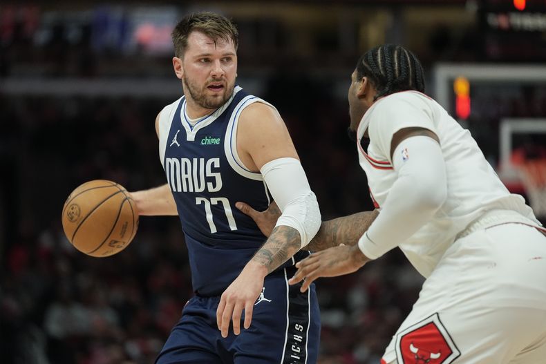 Andre Drummond, derecha, de los Bulls de Chicago, marca a Luka Doncic, de los Mavericks de Dallas, durante la primera mitad del partido de baloncesto de la NBA, el lunes 11 de marzo de 2024, en Chicago. (AP Foto/Erin Hooley)
