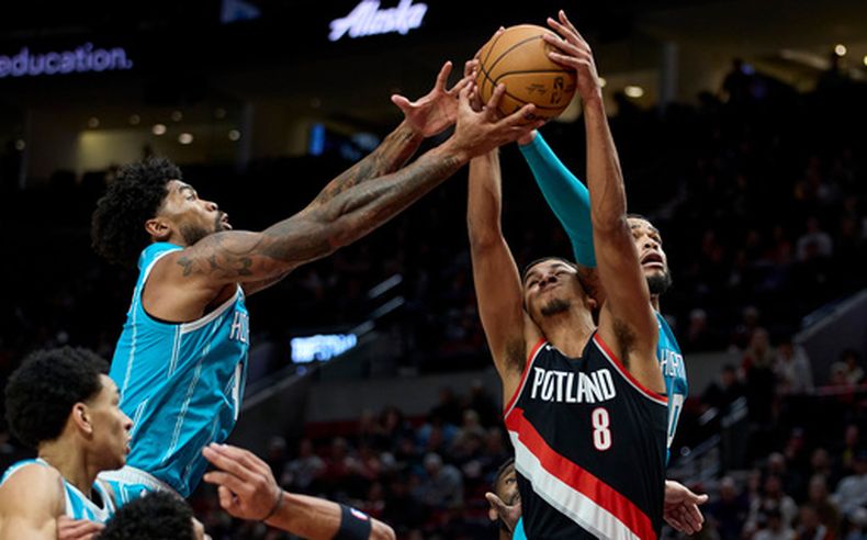 El alero de los Trail Blazers de Portland Kris Murray alcanza el rebote entre el pívot Nick Richards y el alero Miles Bridges de los Hornets de Charlotte el domigno 25 de febrero del 2024. (AP Foto/Craig Mitchelldyer)