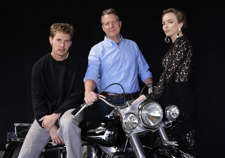 Jeff Nichols, centro, guionista y director de The Bikeriders posa con los miembros del elenco Austin Butler, centro, y Jodie Comer, el jueves 30 de mayo de 2024 en Los Angeles. La motocicleta es una Harley Davidson Pan Head 1965 que Butler montó en la película. (Foto AP/Chris Pizzello)