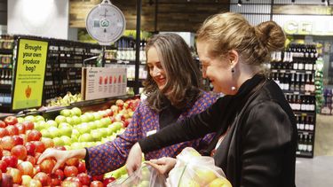 Catherine Langabeer (izquierda), jefa de sostenibilidad de la cadena de supermercado Countdown, y la ministra de Medio Ambiente, Rachel Brooking, muestran como utilizar una bolsa de poliester reutilizable, el 29 de junio de 2023, en Wellington, Nueva Zelanda. (AP Foto/Nick Perry)